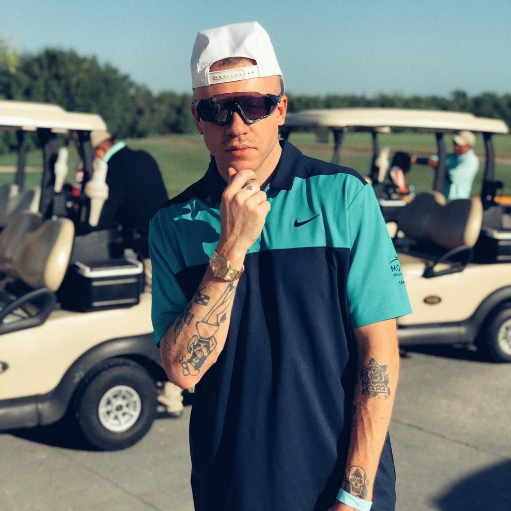 Macklemore standing in front of two golf carts